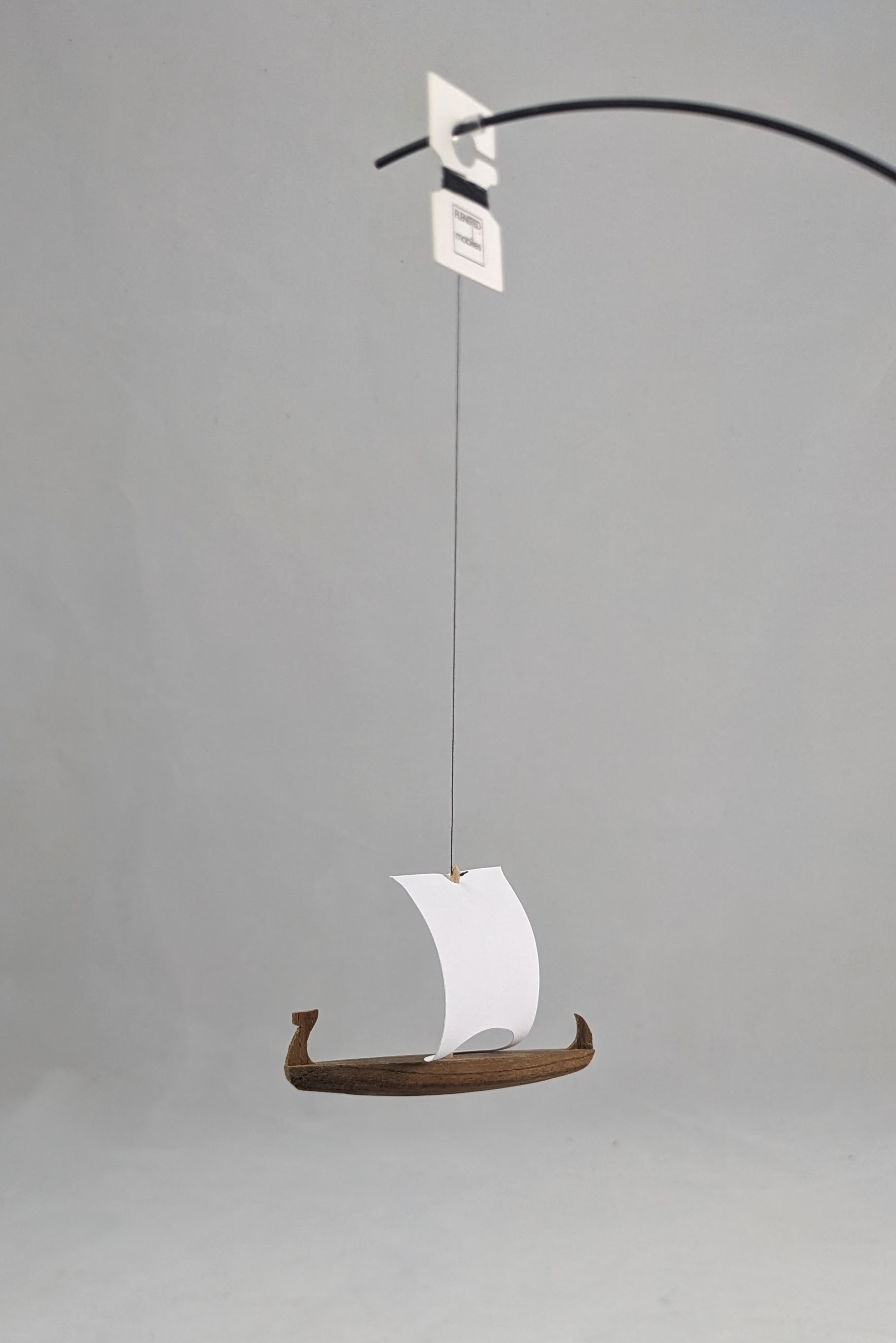 Small wooden ship mobile with a white sail. 