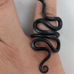 Snake ring that slithers up a finger. The end of the body descends below the knuckle covering a small portion of the hand and the head wriggles up approximately above the first joint of the finger. 