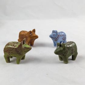 four dala pigs facing each other each in a different color: Light green, burnt orange, pastel blue, and khaki green. 