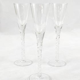 Three aquavit glasses with two in the background and one in the foreground. The stem is twisted to give a subtle texture. 