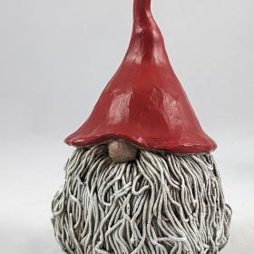 Large Tomte head with a wiry beard, only nose visible poking out from the red pointed hat. 