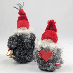 Two examples of the curly wool tomtes, one has a dark gray curly wool coat holding a bell, and the other has a light gray curly wool coat holding a red heart.